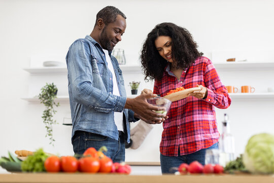 A smiling couple prepares a meal together in a bright, modern kitchen, focusing on healthy eating and togetherness. - Powered by Adobe