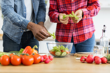 A couple prepares a healthy salad with fresh vegetables in a bright kitchen setting.
