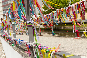 Colorful wish-granting ribbons tied to a bridge over a serene canal, creating a vibrant atmosphere...