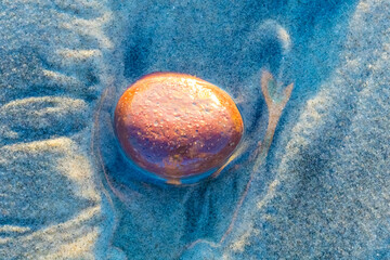 Red stone on the sand, closeup
