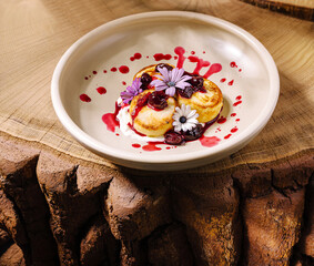 Delicious dessert with flowers and berry sauce on a rustic wooden table