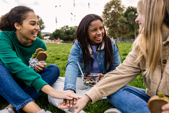 Group of diverse female college friends stacking hands together at university campus