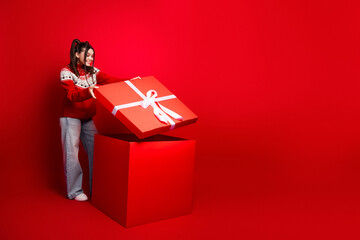 Young woman in red sweater with giant gift boxes in a festive Christmas scene full of joy and magic