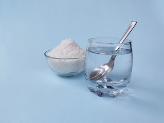 Salt water solution in glass and salt in bowl on blue background 