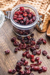 Tasty dried cranberries in jar on wooden table.