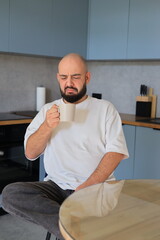 Man reacting with displeasure while looking at his cup of coffee, expressing a negative or unpleasant taste in a kitchen setting