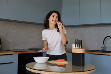 Smiling woman with braces talking in the kitchen while preparing food, cheerful moment during a casual cooking routine at home
