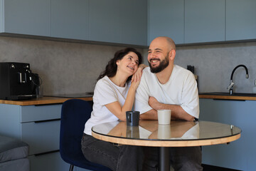 Couple smiling and enjoying a warm, affectionate moment together at the kitchen table, sharing laughter and connection in a relaxed home setting