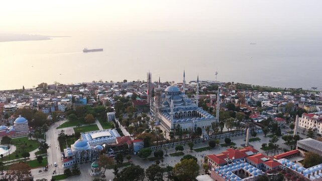 Aerial view of the iconic Blue Mosque set near the waterfront, surrounded by parks and historic buildings at sunset.