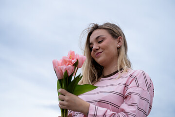Fototapeta premium Young woman smiling holding pink tulip bouquet