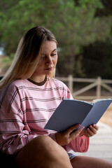 Obraz premium Young woman enjoying leisure time reading book outdoors