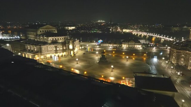 Night view over Theatre Square in Dresden featuring the brightly lit Semperoper and the wide plaza under a clear dark sky.