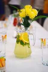 Refreshing lemonade pitcher with garnishes on dining table