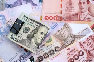 Thai baht currency money bills and bunch of us dollar banknotes close up. The concept of economics and currency exchange