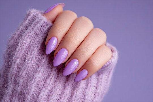 A woman's hand with purple manicure on long nails on a lilac background