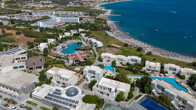 Aerial view of azure waters meet sun-kissed sands, fringed by modern resorts and villas, a vibrant tapestry of Greek island life, Kolympia, Rodos, Greece.