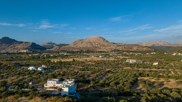Aerial view of the rugged mountains and verdant olive groves meet the clear blue sky, creating a serene landscape, Kolympia, Rodos, Greece.