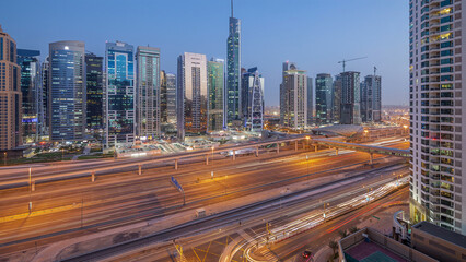 Fototapeta premium Aerial view of Jumeirah lakes towers skyscrapers day to night timelapse with traffic on sheikh zayed road.