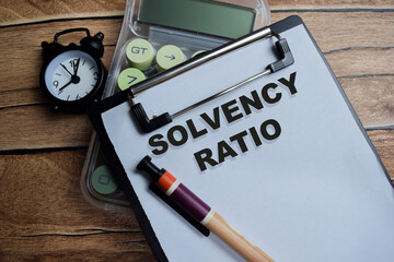 Concept of solvency ratio write on clipboard isolated on Wooden Table.
