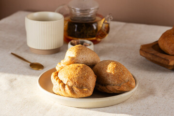 Freshly baked golden pies with apples, pears, and cinnamon made from whole grain flour with tea in a teapot on a table.
