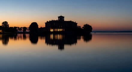 Naklejka premium Silhouette of a building on an island at sunset reflecting on water