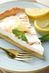 Slice of tasty lemon meringue tart served on table, closeup