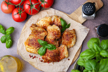 Tasty roasted chicken thighs with basil, spices and tomatoes on grey table, flat lay