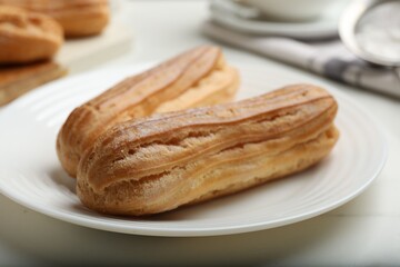 Delicious eclairs served on white table, closeup