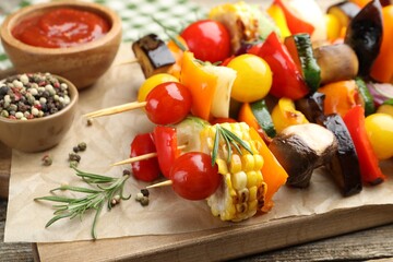 Skewers with tasty grilled vegetables, sauce and peppercorns on wooden table, closeup