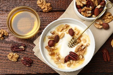 Delicious Greek yogurt with honey and nuts served on wooden table, flat lay