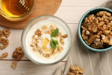 Delicious Greek yogurt with honey and walnuts served on white wooden table, flat lay