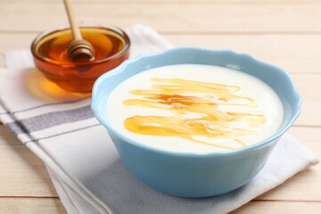 Delicious Greek yogurt with honey served on white wooden table, closeup