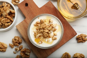 Delicious Greek yogurt with honey and walnuts served on white table, flat lay