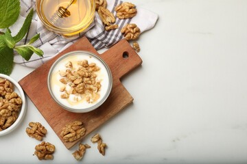Delicious Greek yogurt with honey and walnuts served on white table, flat lay. Space for text