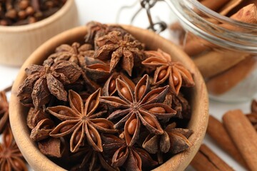Mulled wine spices. Anise stars in wooden bowl and cinnamon sticks on white table, closeup