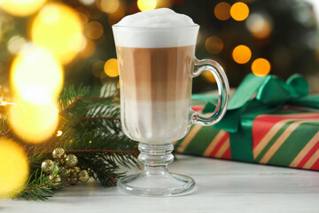 Aromatic coffee and Christmas decor on white wooden table against blurred lights, closeup