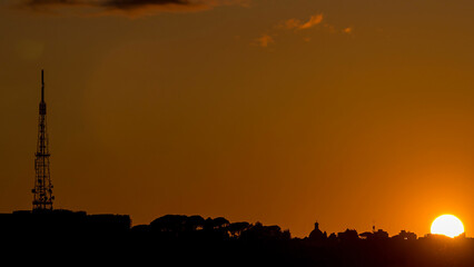 Rome at sunset timelapse with the fiery orb of the sun dropping below the horizon above the rooftops of the historical buildings