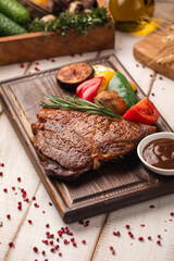 Juicy grilled steak served with roasted vegetables and herbs on wooden board