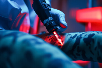 A tattoo artist carefully creates a colorful design on a person's leg in a stylish studio illuminated by vibrant lights at night