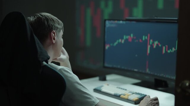 Confused male trader experiencing stress and financial loss sitting at computer desk, seeing declining stock market chart on monitor. Concept of online trading and investment. Shooting in slow motion.