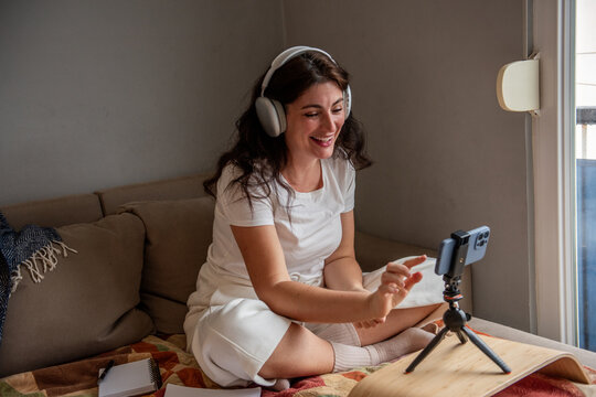 Woman blogging at home with smartphone and headphones