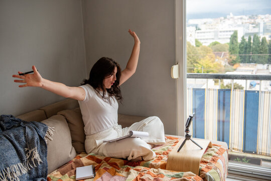 Woman blogging from home with smartphone and notebook
