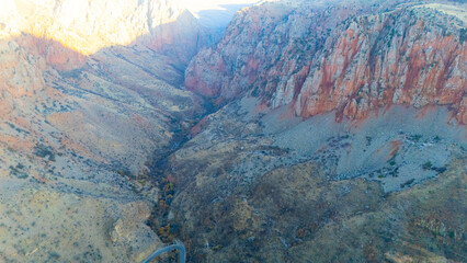 Top-down drone view of a winding asphalt road cutting through bright red earth and dry terrain....