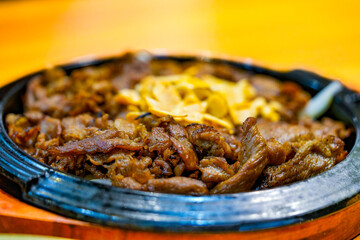 Bulgogi served in a hot plate and sprinkled with dry garlic. Korean food.