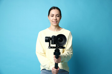 Obraz premium Videographer using gimbal stabilizer with camera on light blue background