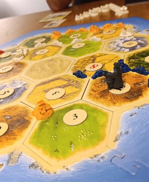 Catan - Jogo de tabuleiro moderno onde os jogadores competem para colonizar uma ilha, construindo estradas, vilas e cidades. O jogo envolve coletar e negociar recursos.