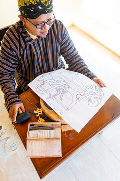 Artisan Showing Wayang Kulit Puppet Design Sketch with Tools