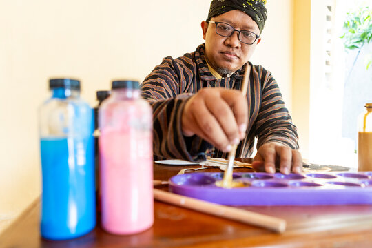 Traditional Artist Mixing Paints for Wayang Kulit Puppet Craft