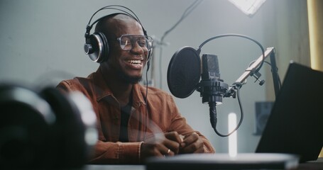 Voice Actor Records Professional Dubbing For Film or Media Project. Man at Laptop Recording Audio With Professional Studio Microphone. Technical Process Voiceover For Films, Commercials, Multimedia.