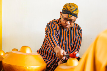 Traditional Java gamelan musician playing an instrument